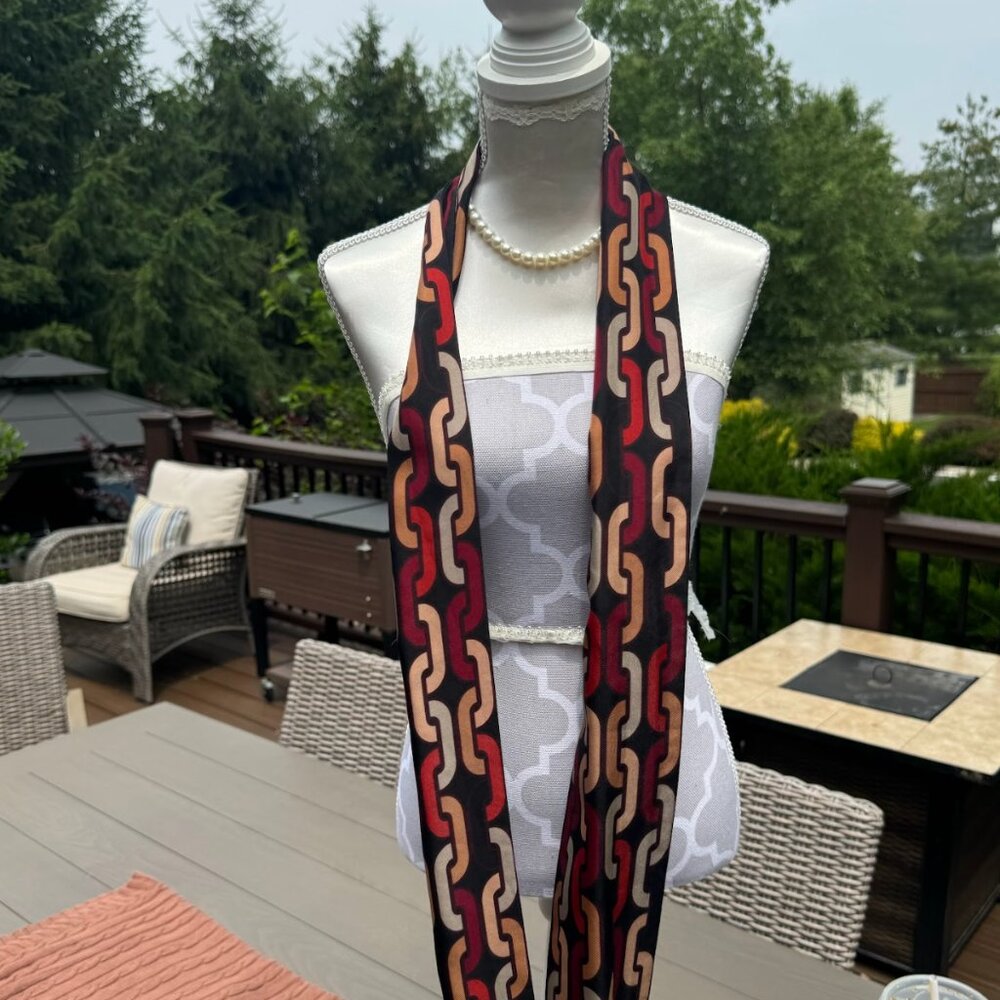 Sleek and statement-making, this vintage silky scarf features a bold chain link